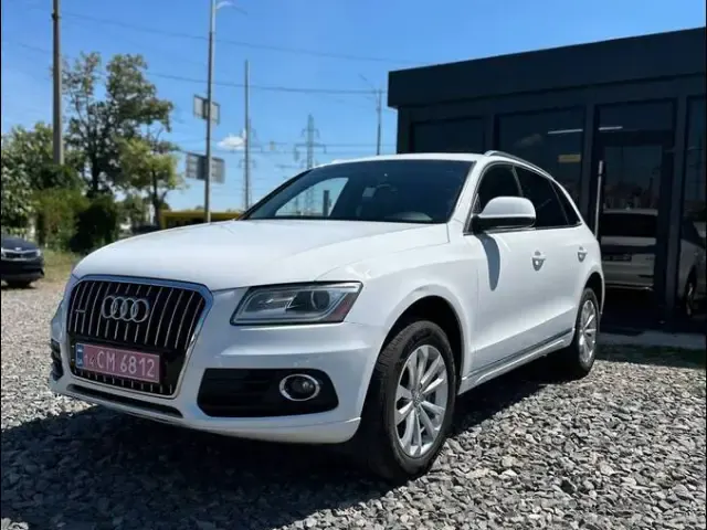 Білий Audi Q5 на гравійному майданчику біля чорного павільйону