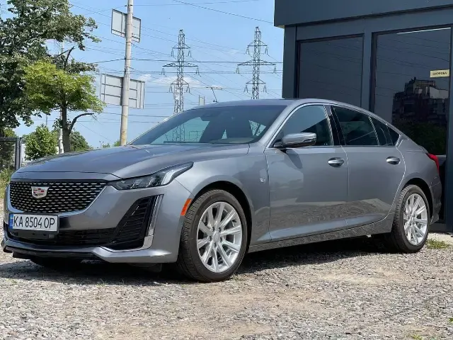 Grey Cadillac CT5 on a gravel lot by a black pavilion
